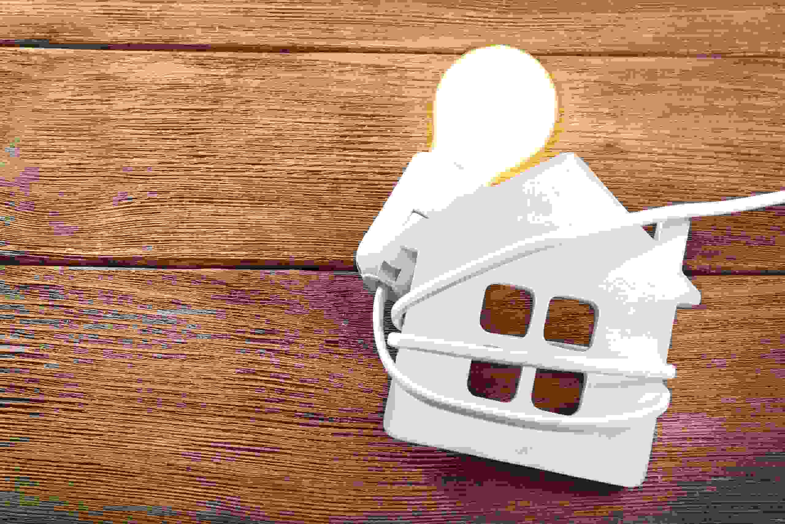 White house-shaped lamp with lit bulb on wooden surface, showcasing electrical features for Southwest Florida Electric Inc.