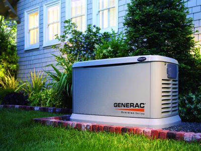 Standby generator installed in residential yard, providing backup power during outages, featuring Generac branding and surrounded by landscaping.