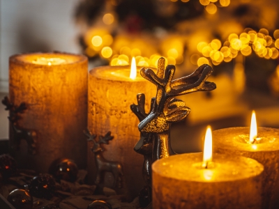 Candles with warm flames and a decorative reindeer figurine, emphasizing holiday safety tips for managing electrical decorations and fire risks.