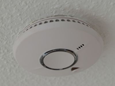 Smoke detector mounted on a ceiling, highlighting essential home safety equipment for fire detection and alerting, relevant to electrical safety measures.