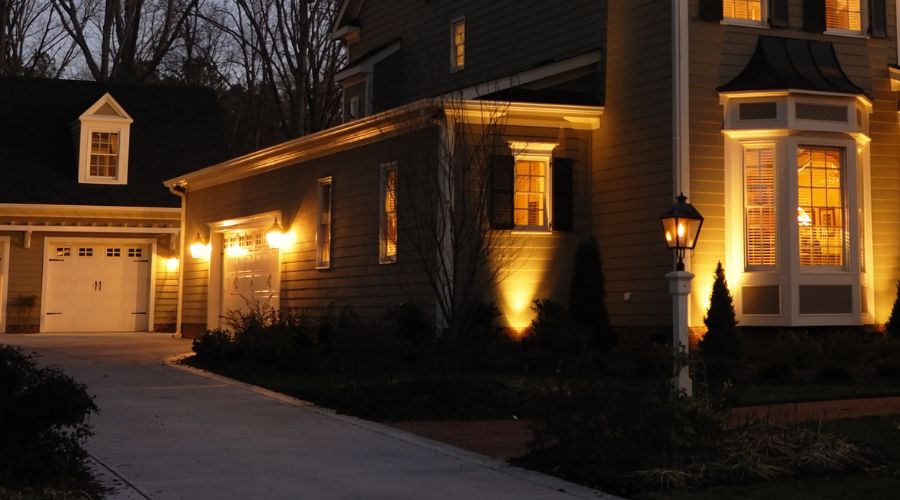 Outdoor residential lighting illuminating a house facade and driveway at dusk, enhancing safety and ambiance for outdoor spaces.