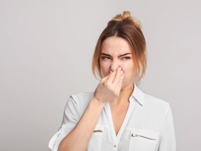 Woman holding her nose, expressing disgust, illustrating the unpleasant odors associated with faulty electrical wiring.